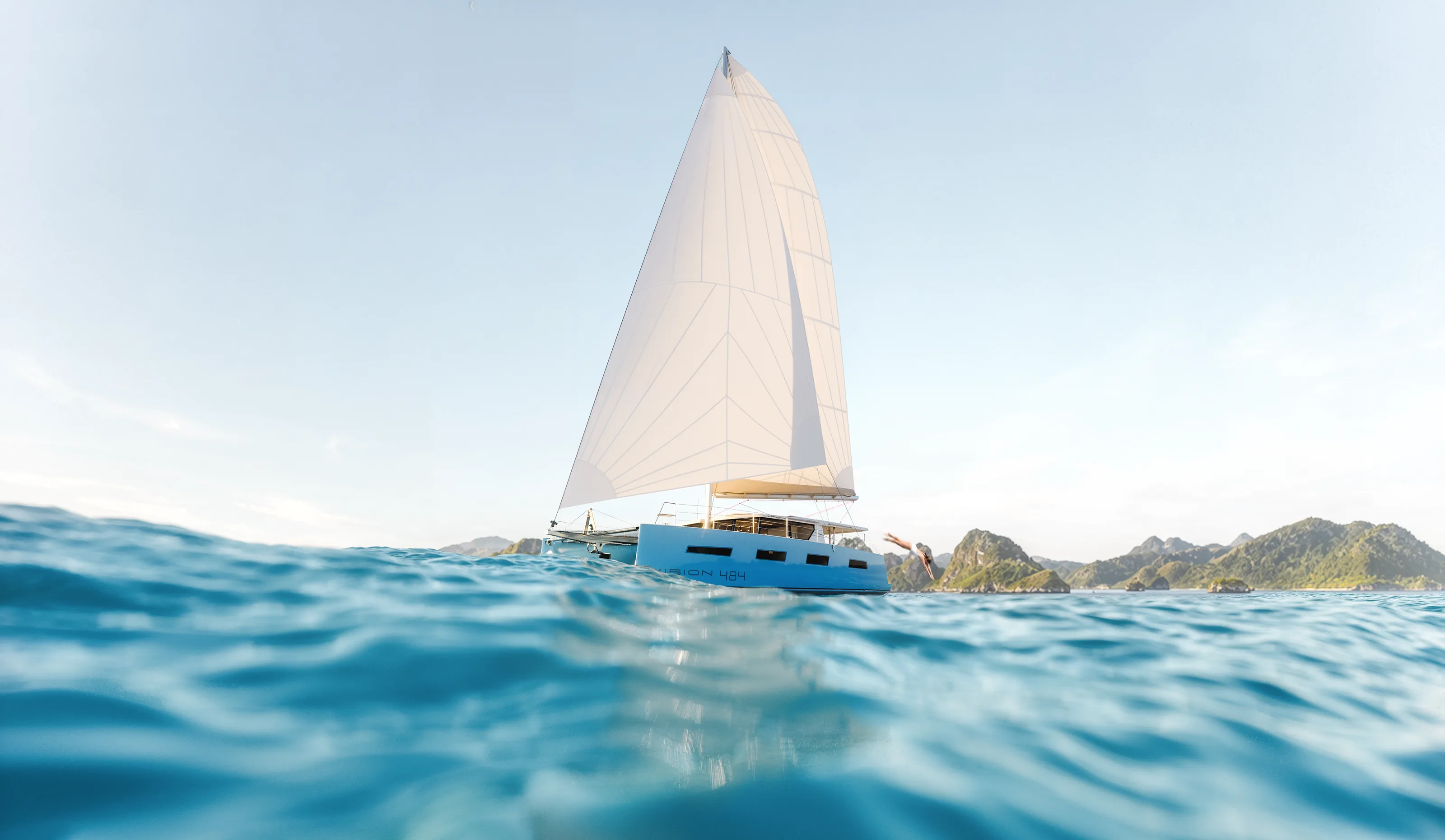 The Vision 484 under full sail in turquoise water, seen low from the surface with islands behind